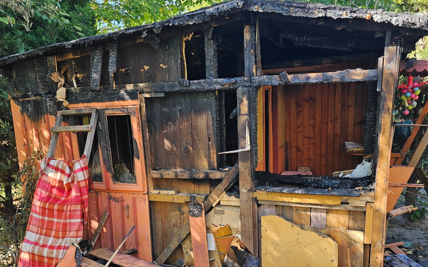 
        Zniszczona chatka po pożarze, widoczne uszkodzenia.
    