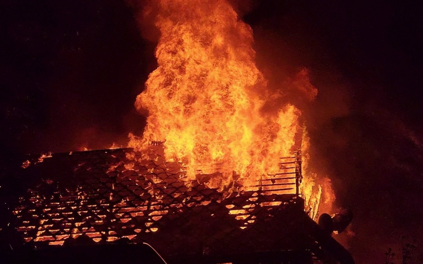 
        Widok na płonący budynek w nocy, dramatyczna sytuacja.
    