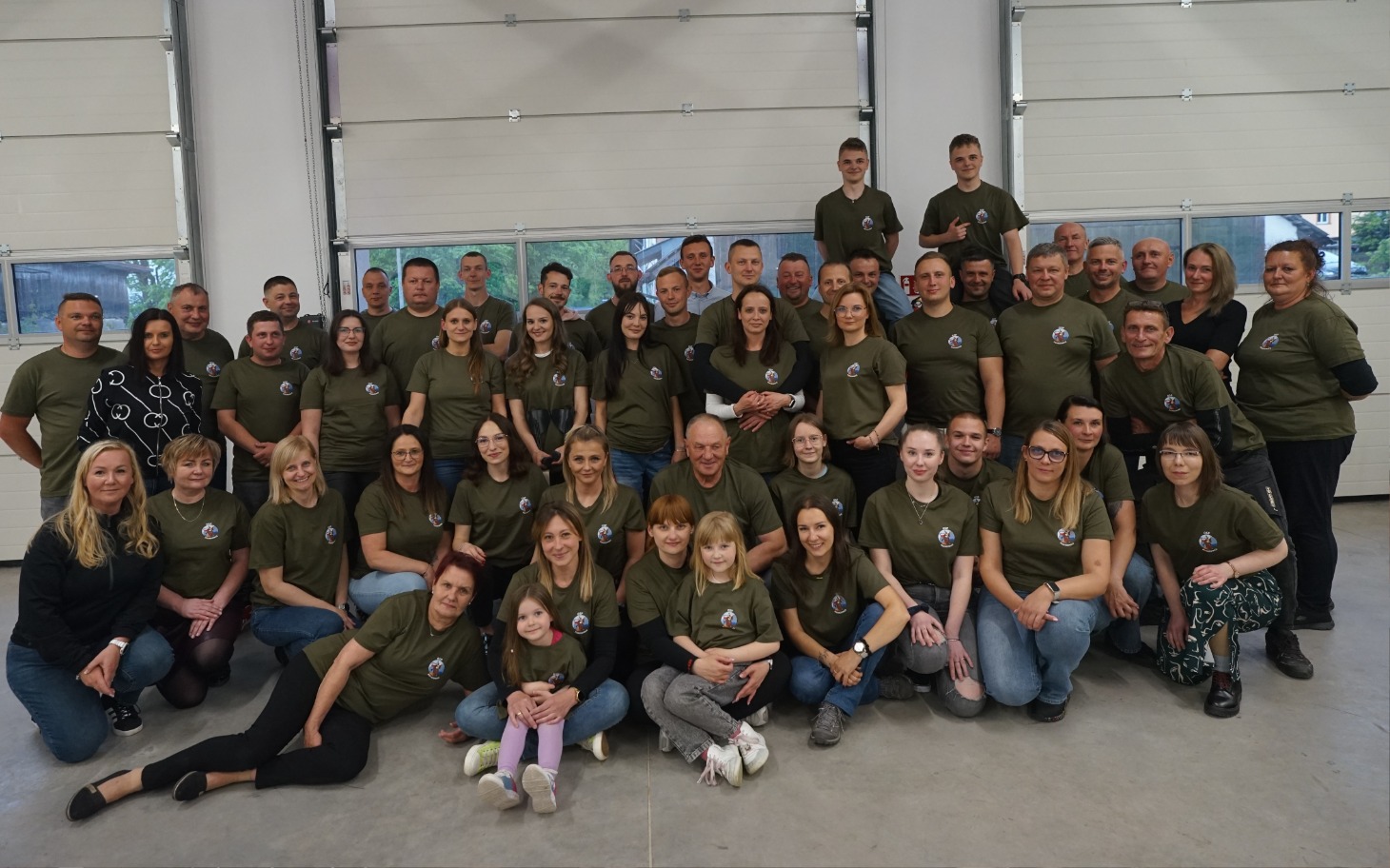 
        Grupa ludzi w zielonych koszulkach, pozująca do zdjęcia.
    