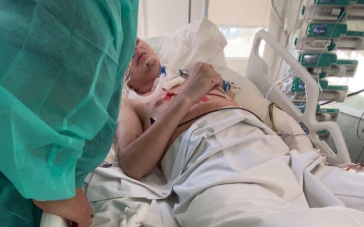 
        Mężczyzna leżący w szpitalu, otoczony sprzętem medycznym.
    