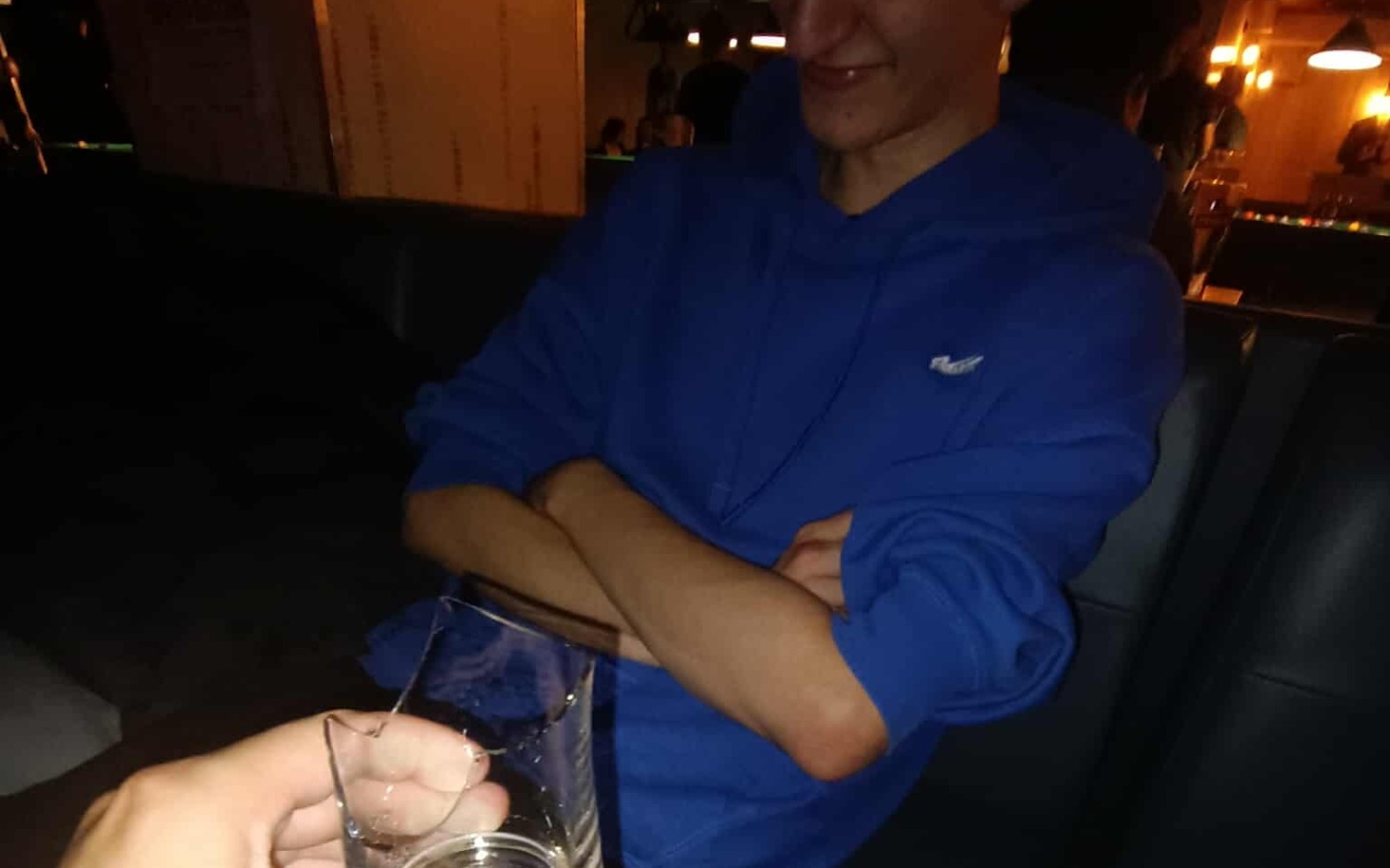 
        Mężczyzna w niebieskiej bluzie, siedzący w barze z drinkiem.
    