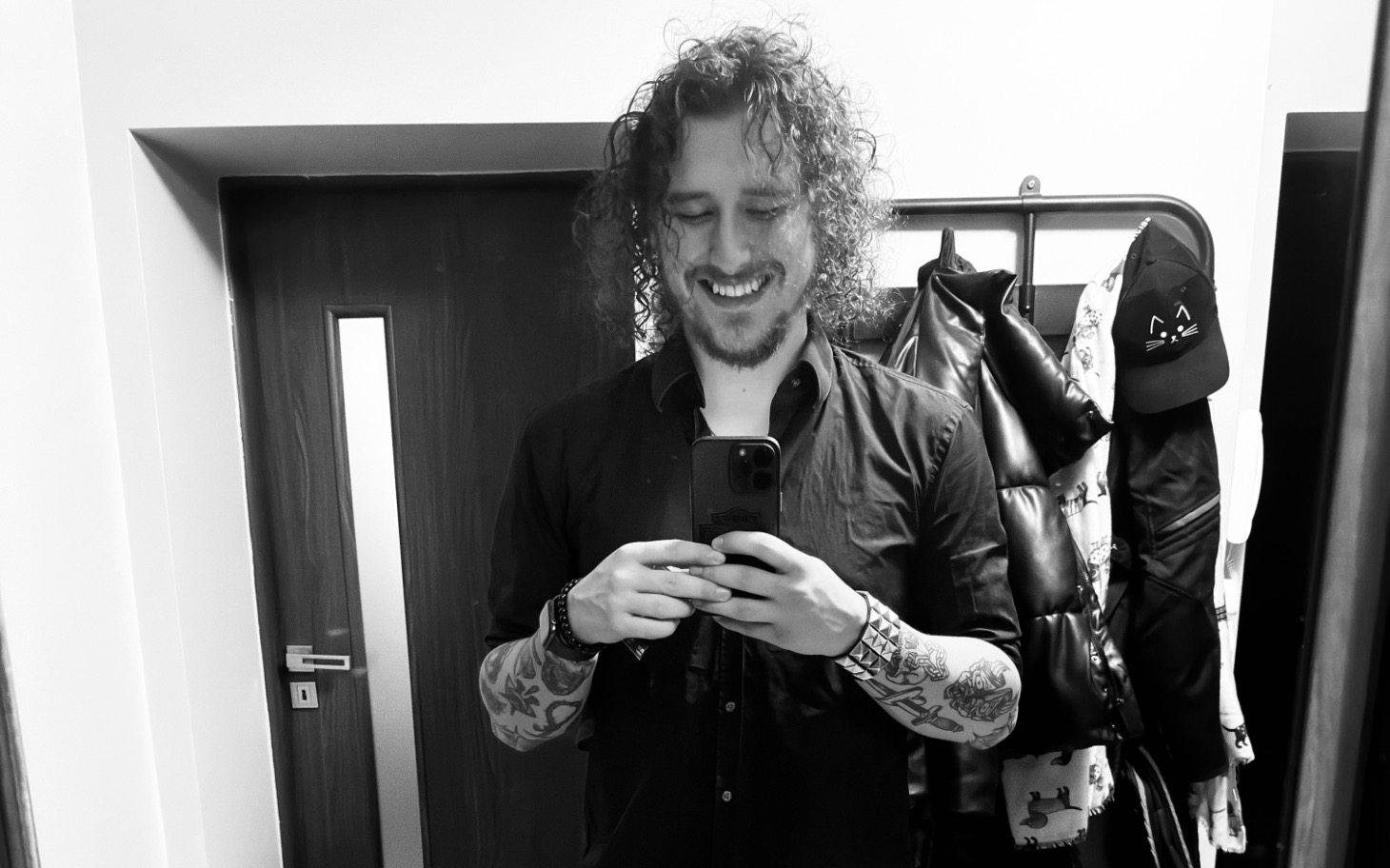 Mężczyzna w czarnej koszuli, uśmiechający się do lustra.