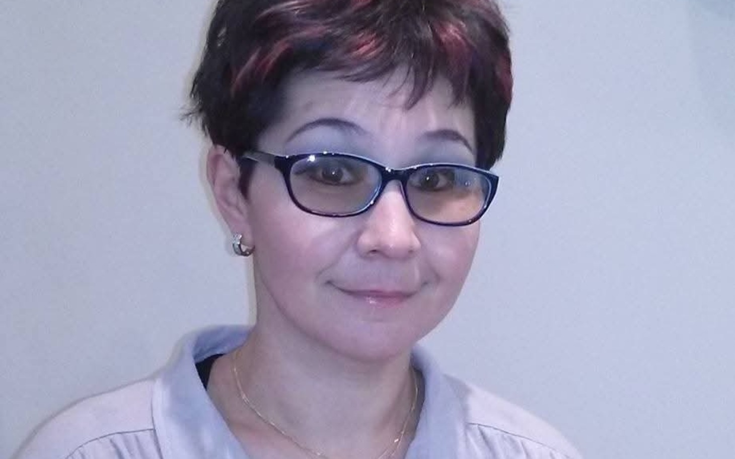 
        Kobieta w okularach, uśmiechająca się do kamery.
    
