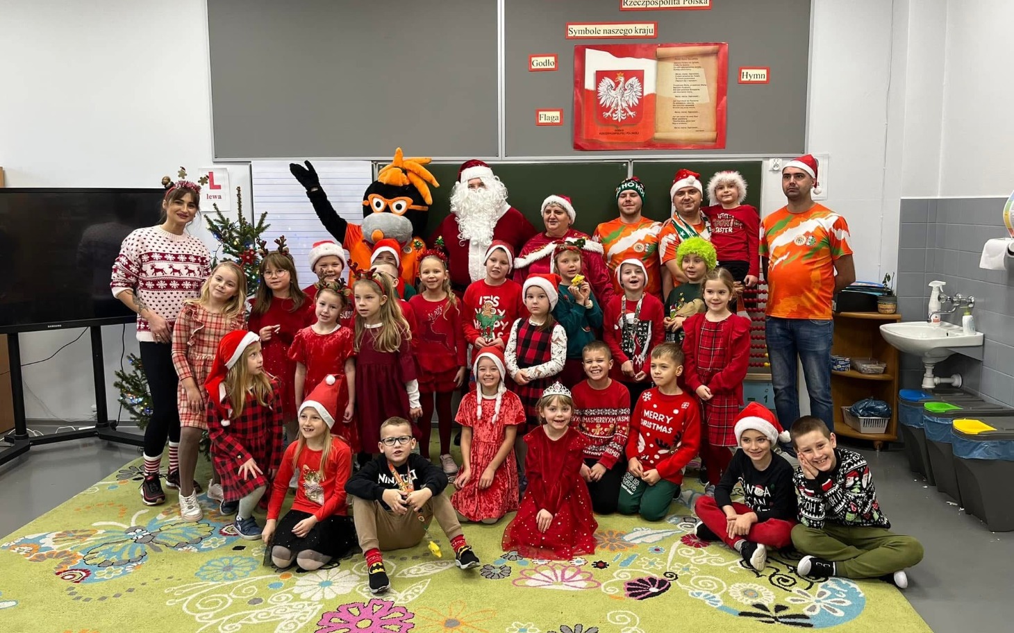 Grupa dzieci w strojach świątecznych z Mikołajem.