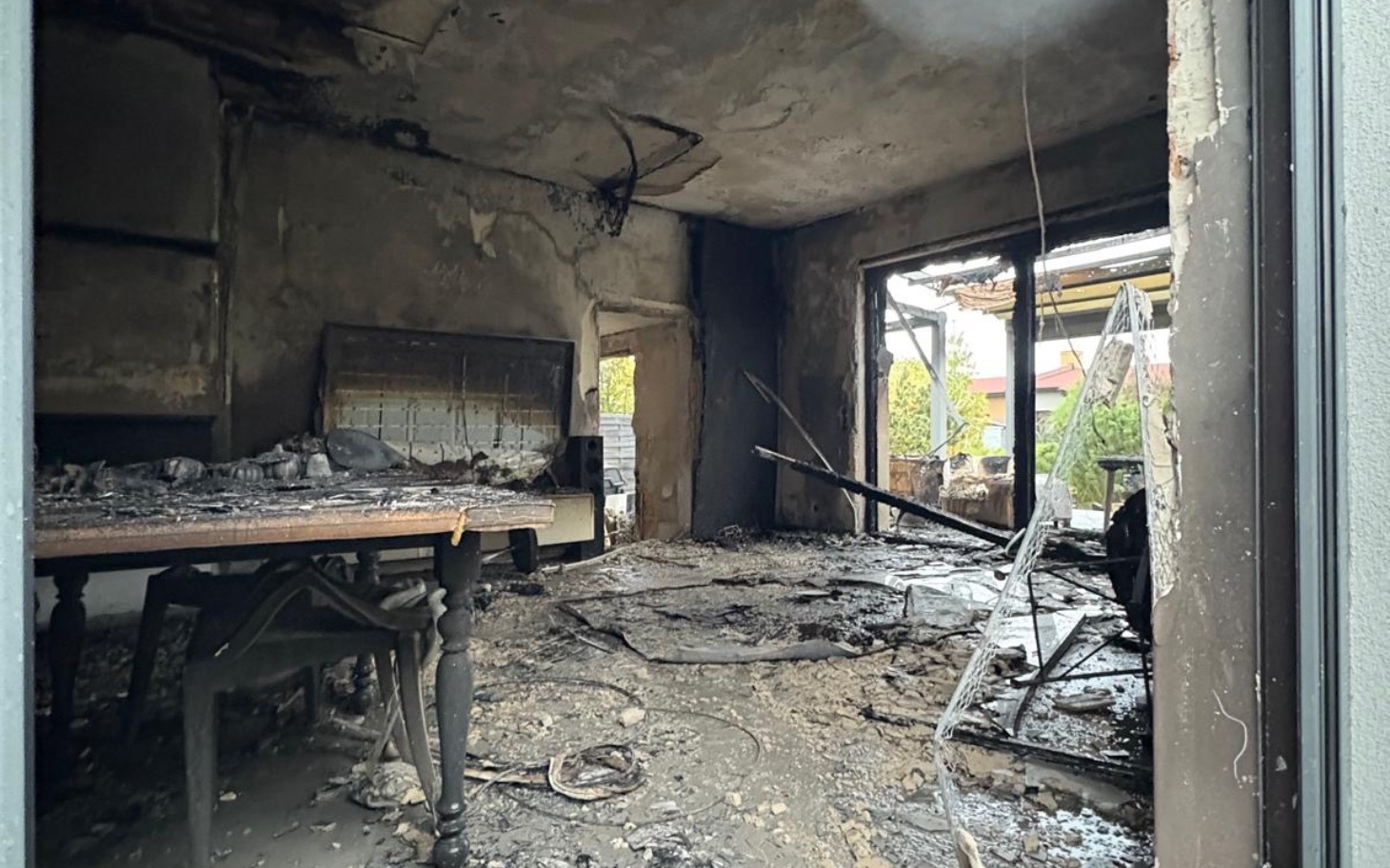 Zniszczone wnętrze po pożarze, z popiołem i zniszczeniami.