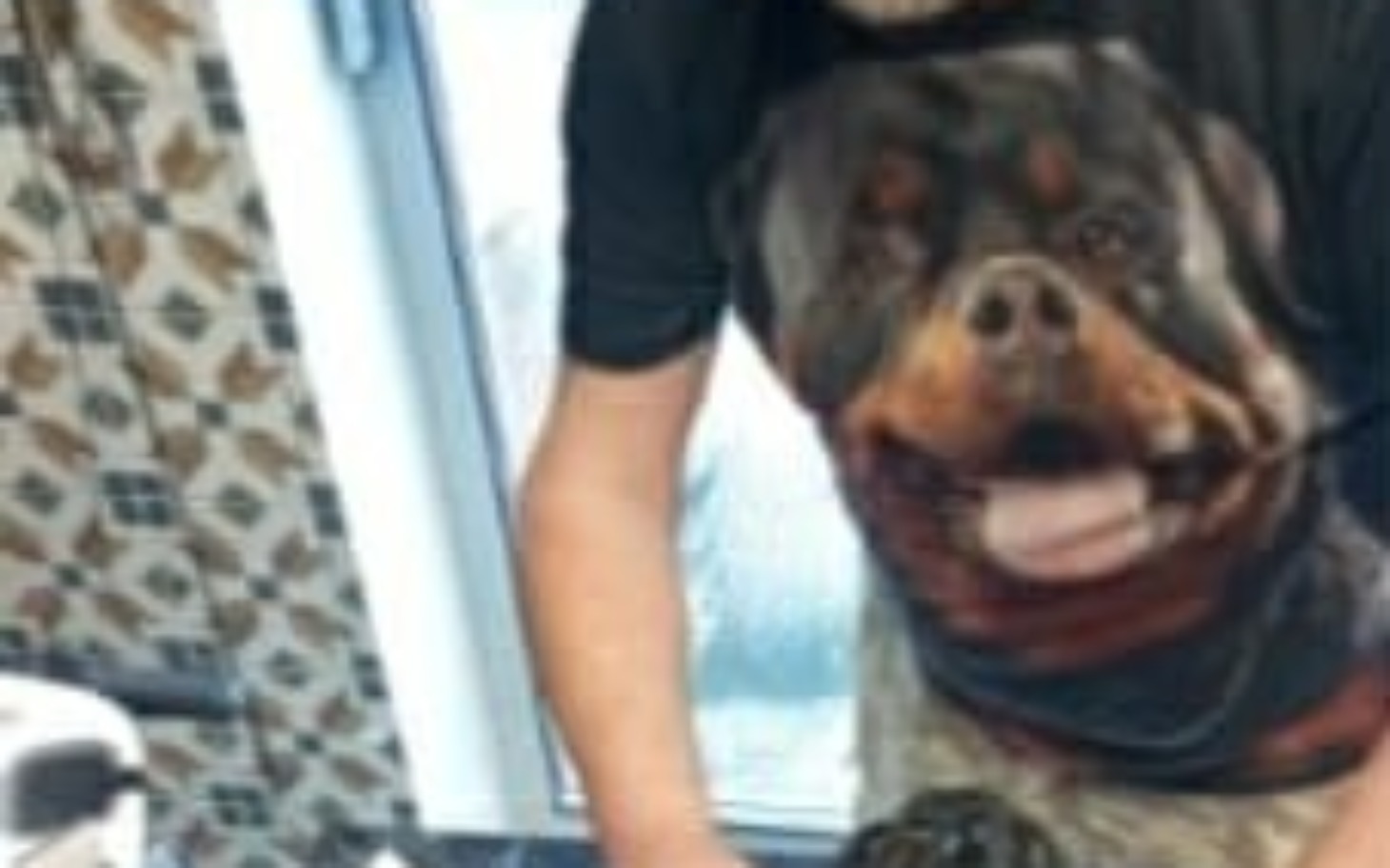 
        Mężczyzna z psem na koszulce, uśmiechając się w kuchni.
    