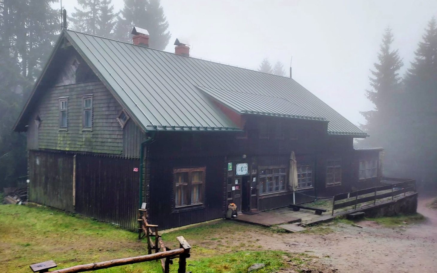 Drewniany domek w lesie, otoczony mgłą.