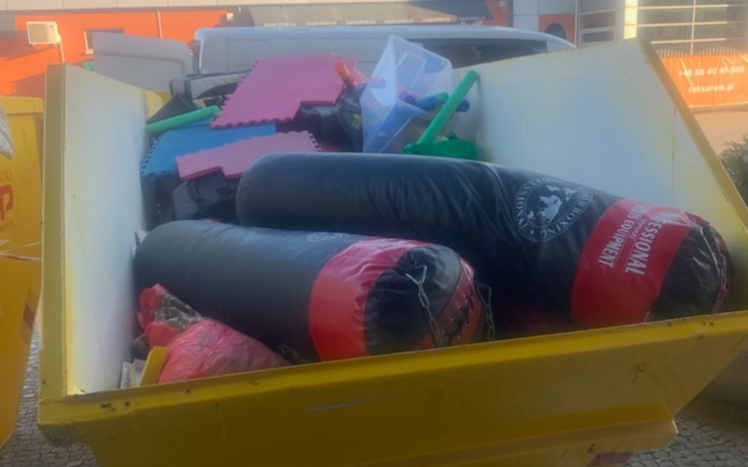 
        Kontener z różnymi przedmiotami, w tym workami do ćwiczeń.
    