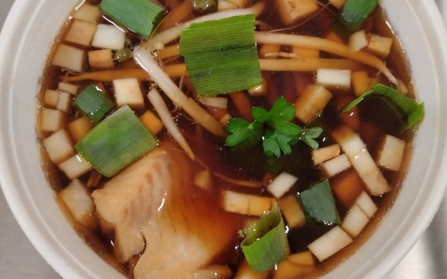 
        Zupa z kawałkami mięsa i warzywami w misce.
    