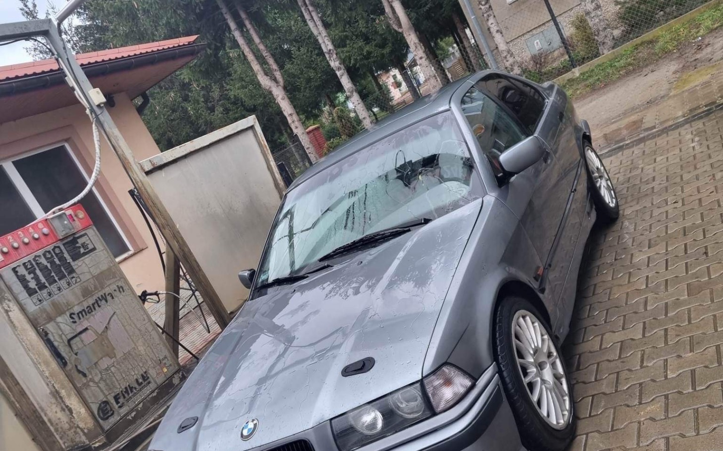 
        Szary samochód BMW zaparkowany na podjeździe.
    