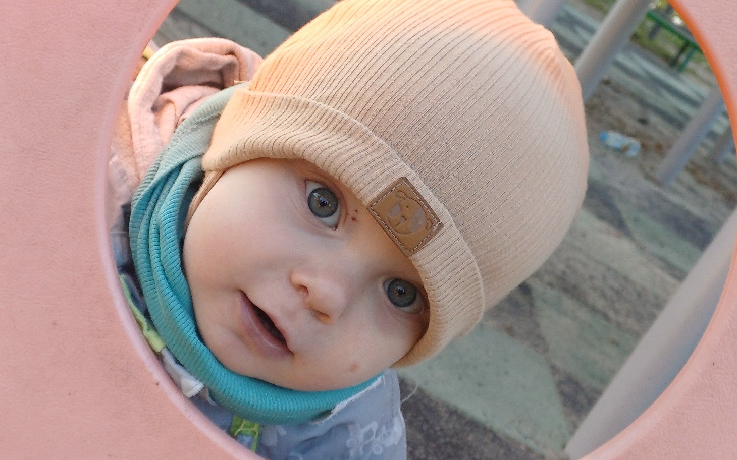 
        Małe dziecko w czapce bawi się na placu zabaw.
    