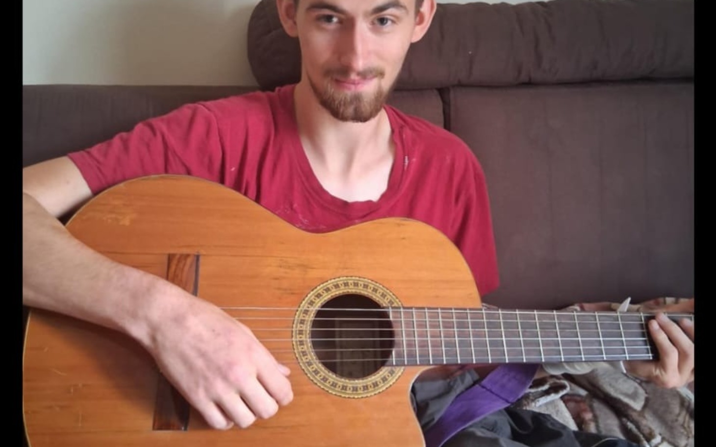 
        Mężczyzna grający na gitarze, uśmiechnięty.
    