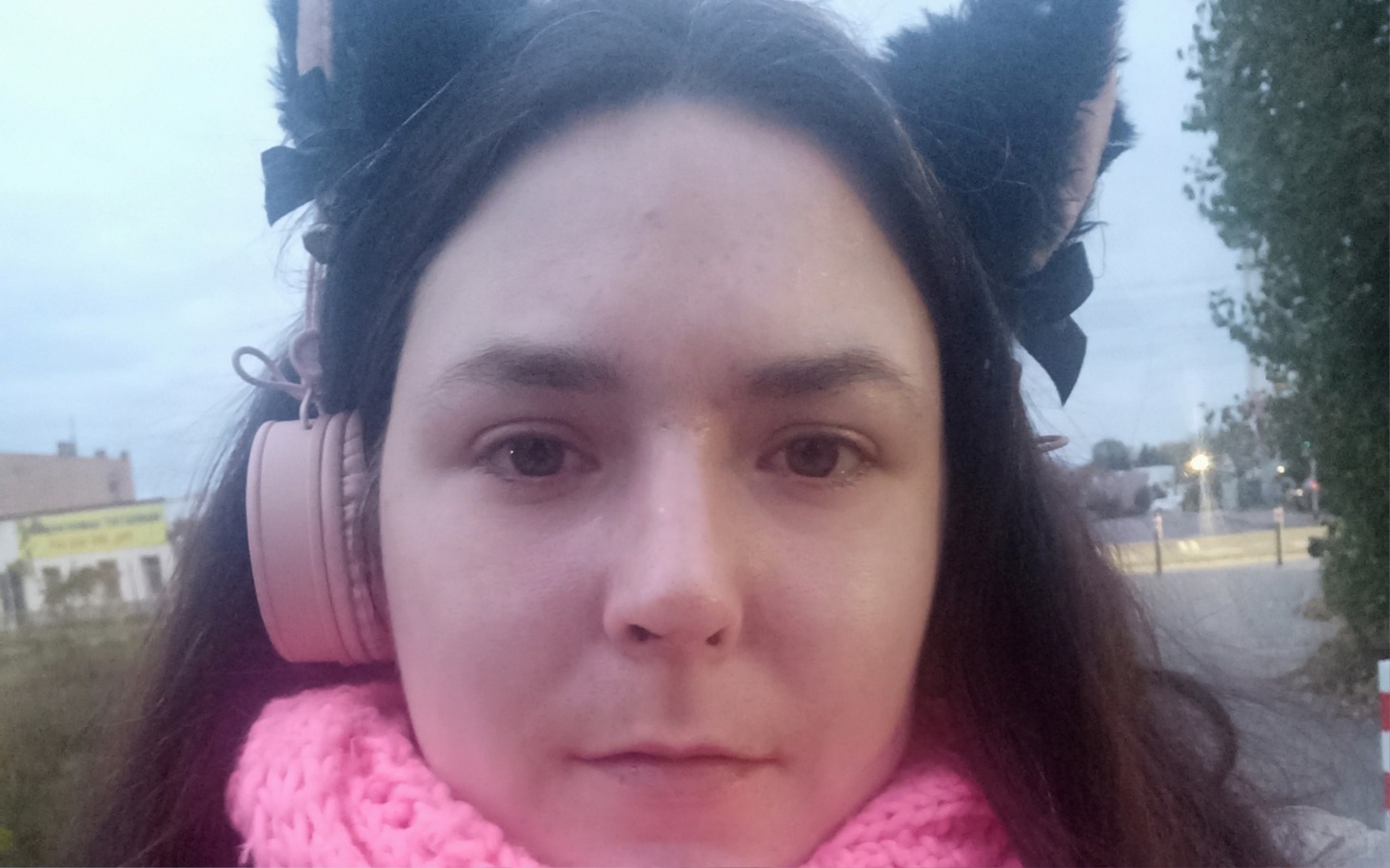 
        Kobieta w różowym szaliku i słuchawkach, na zewnątrz.
    