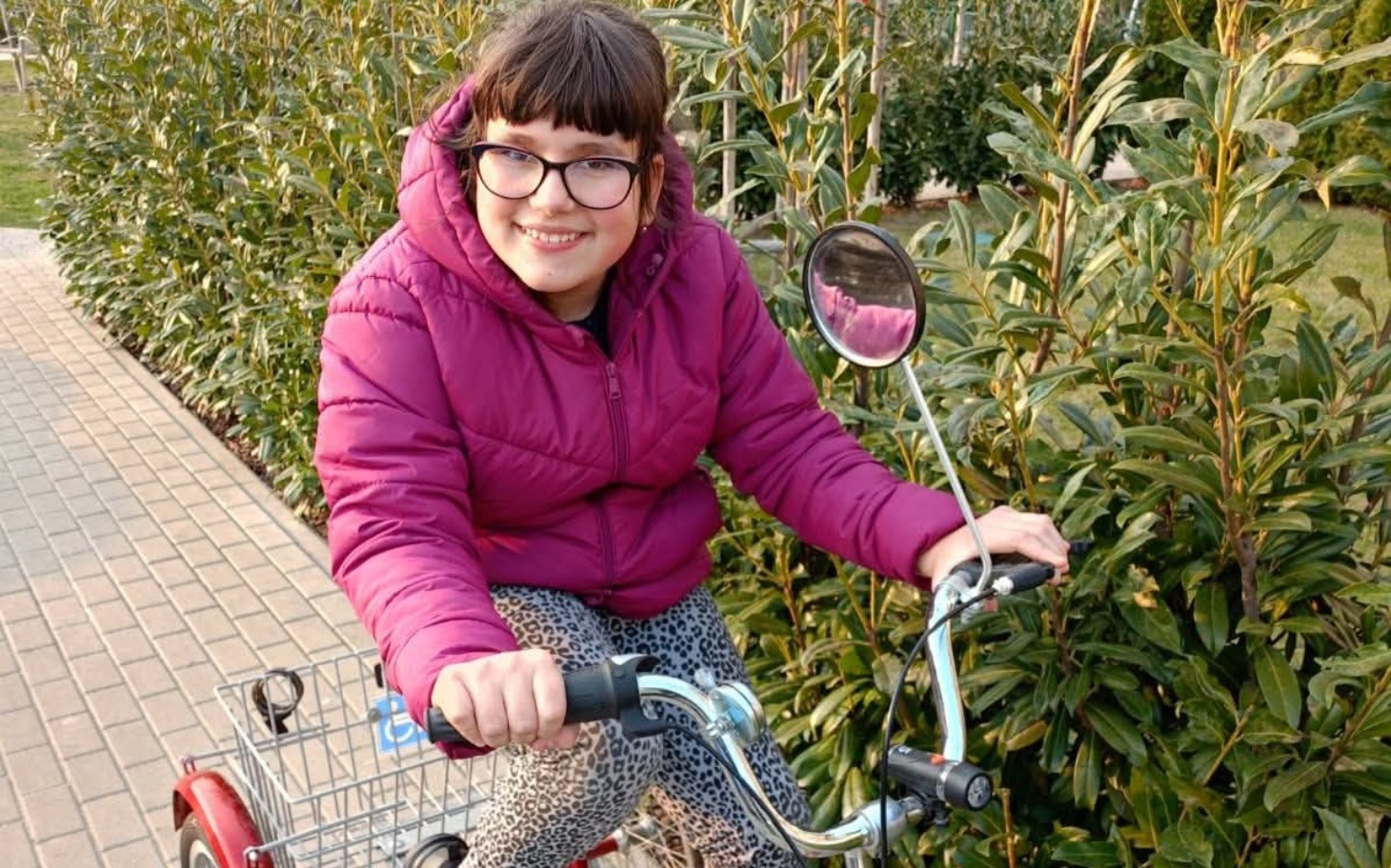 
        Uśmiechnięta dziewczynka na rowerze w parku.
    