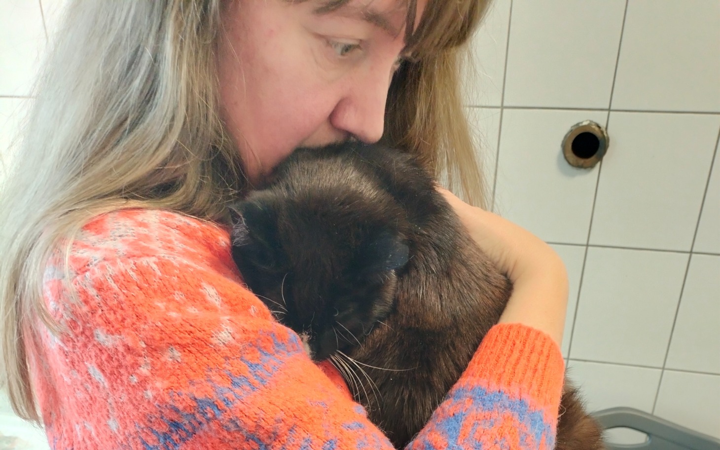 
        Kobieta przytulająca kota, wyrażająca miłość i troskę.
    