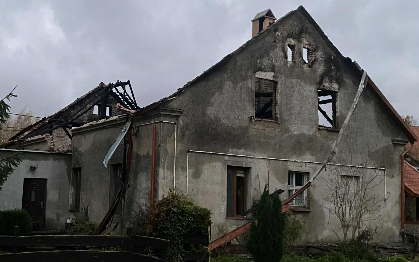 
        Zniszczony dom po pożarze, z widocznymi uszkodzeniami.
    