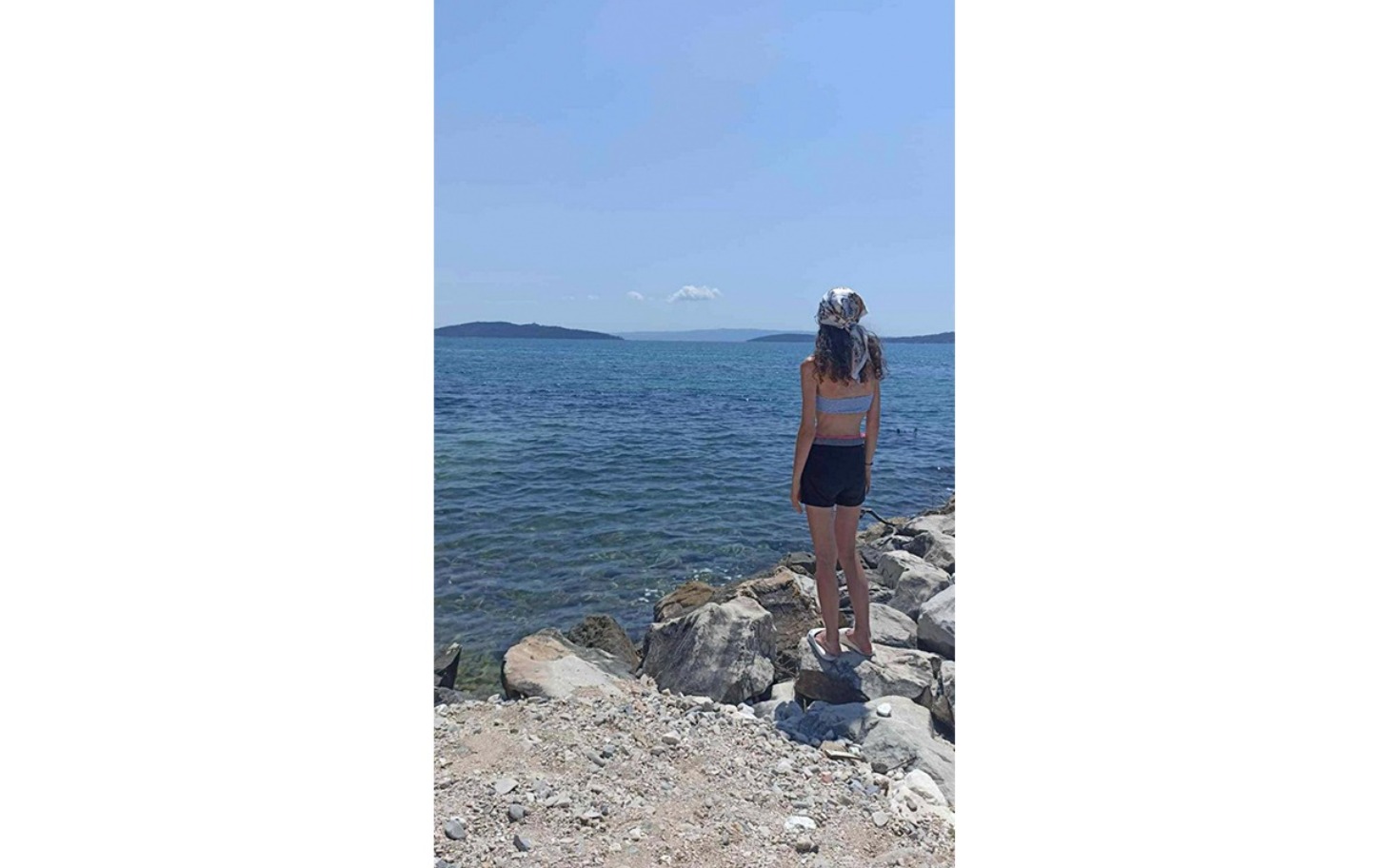 
        Kobieta stojąca na brzegu morza, patrzy na wodę.
    