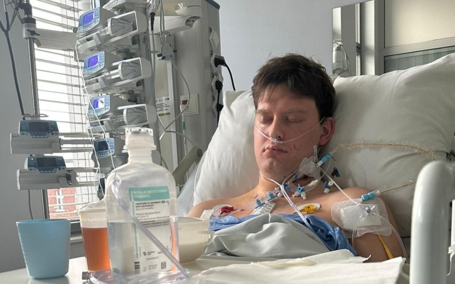 
        Młody mężczyzna w szpitalu, podłączony do aparatury medycznej.
    