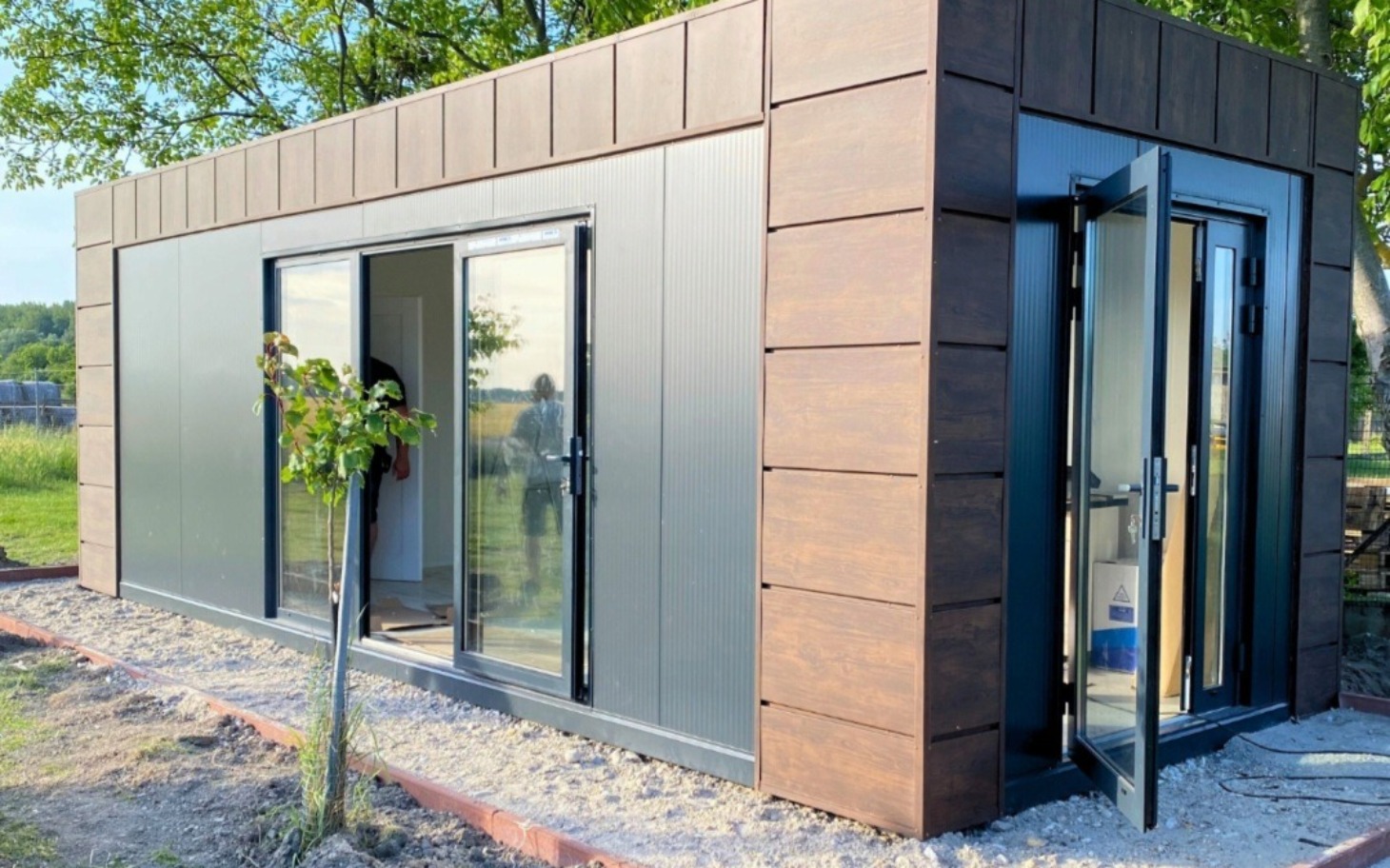 
        Nowoczesny domek z dużymi oknami, w otoczeniu zieleni.
    