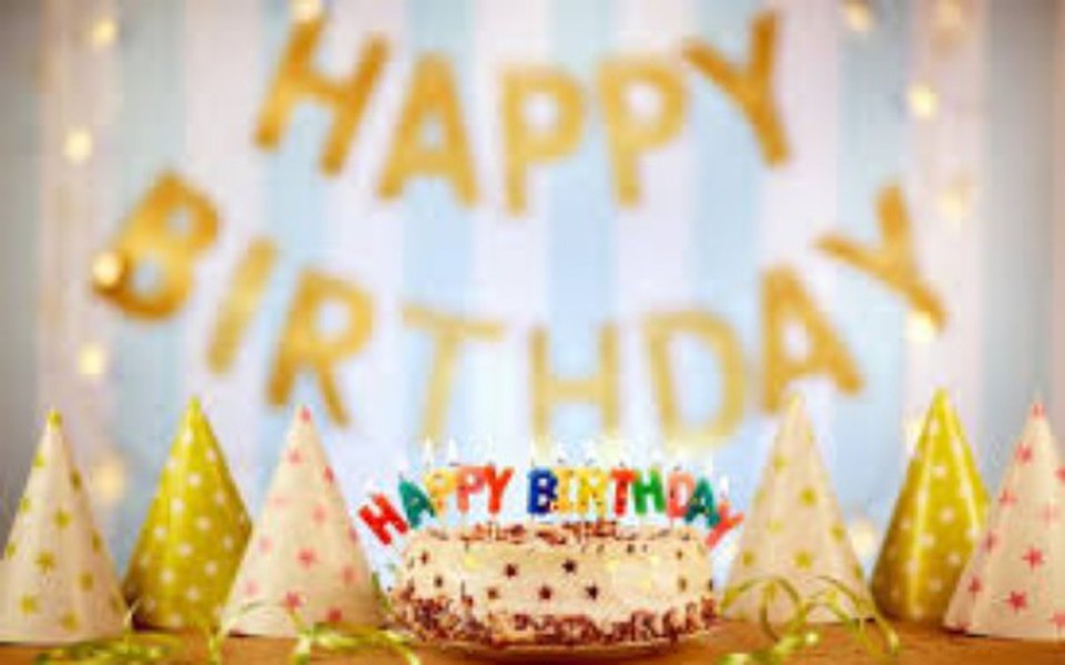 
        Tort urodzinowy z napisem 'Happy Birthday' i kolorowymi czapkami.
    