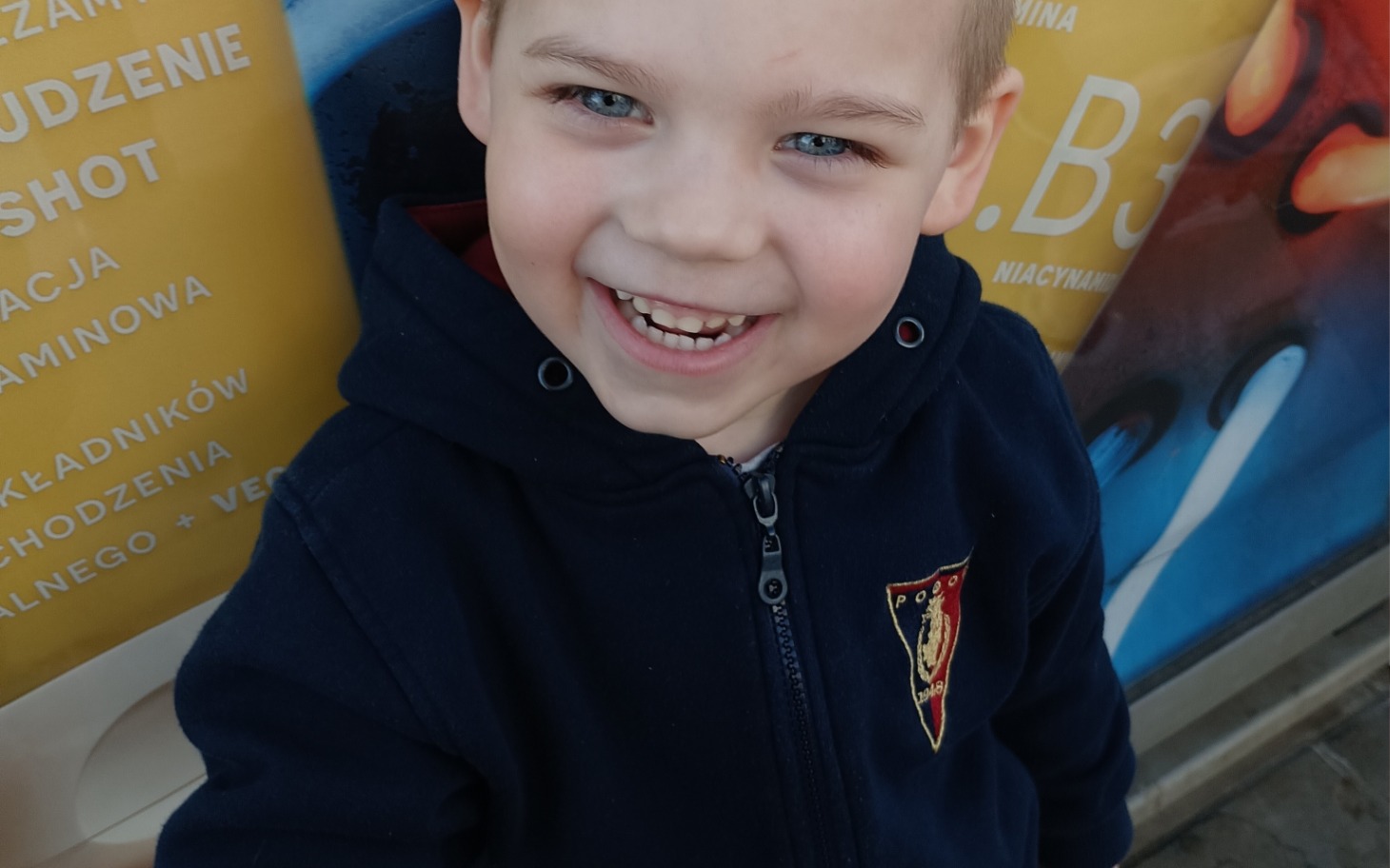
        Uśmiechnięty chłopiec w bluzie, pozujący do zdjęcia.
    