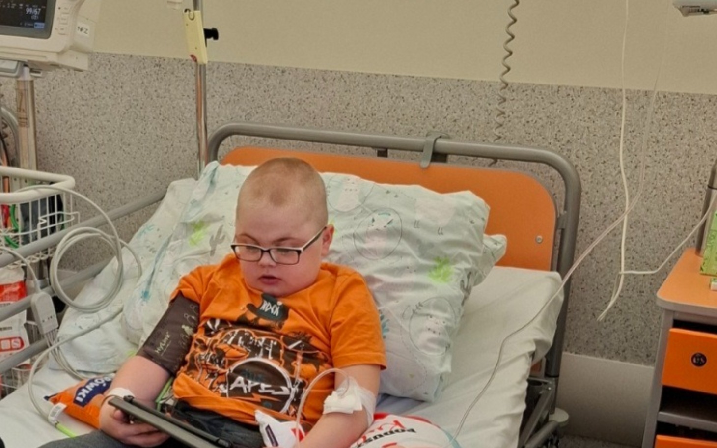 
        Chłopiec w szpitalu, skupiony na tablecie.
    