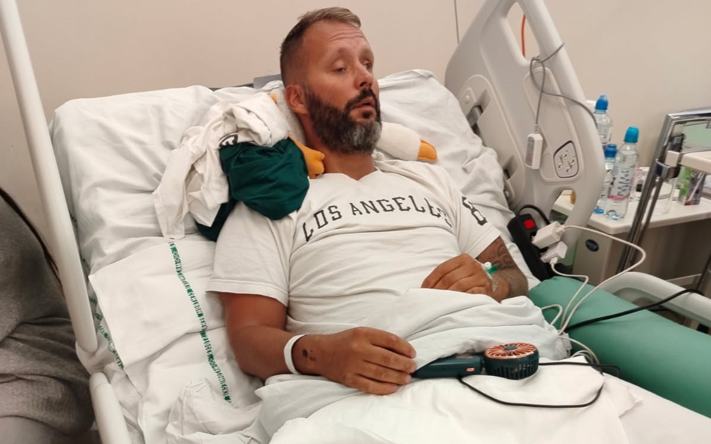 
        Mężczyzna leżący w szpitalnym łóżku, wygląda na zmęczonego.
    