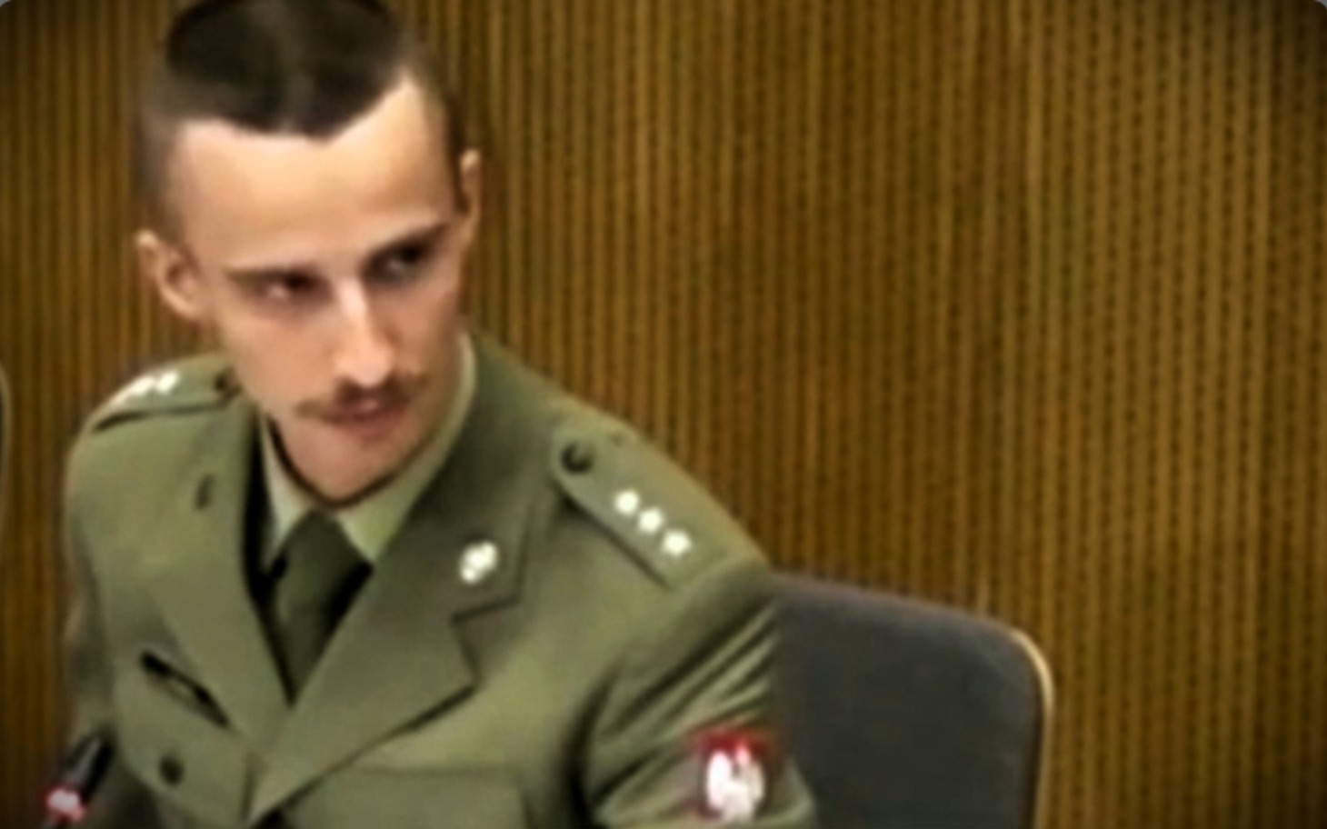 
        Mężczyzna w mundurze wojskowym podczas przesłuchania.
    