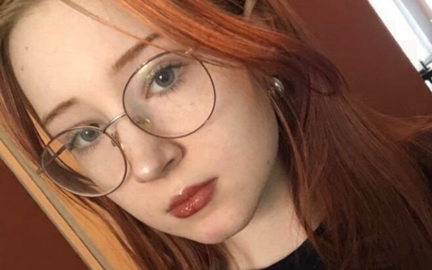 
        Portret młodej kobiety z rudymi włosami i okularami.
    