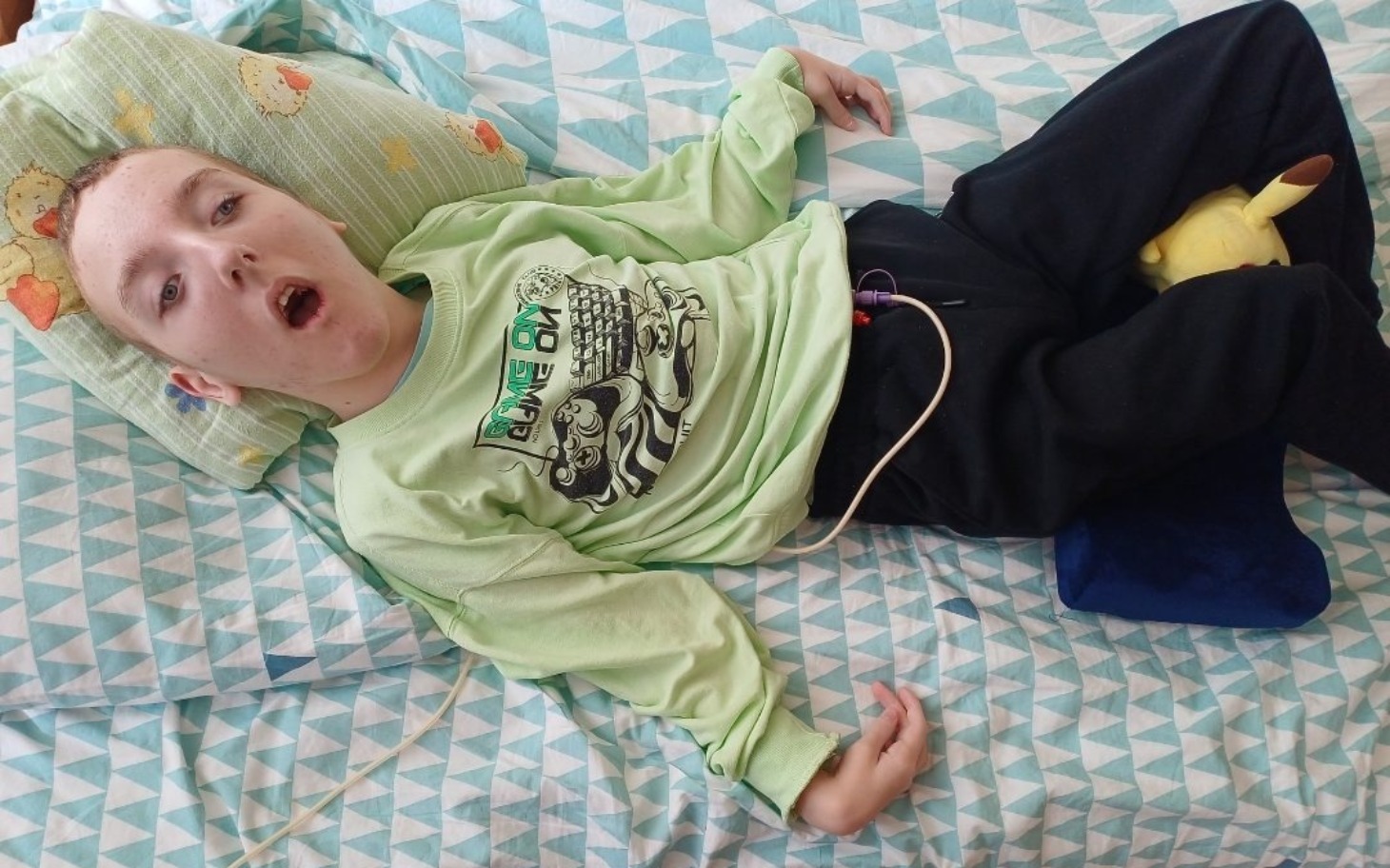 
        Chłopiec leżący na łóżku z rurką dożylną.
    