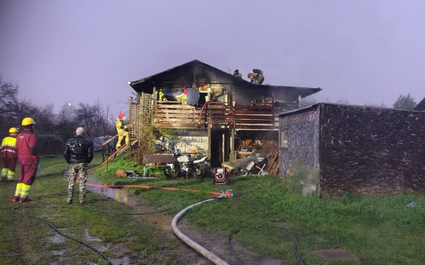 
        Strażacy gaszą pożar w drewnianym budynku, akcja ratunkowa.
    