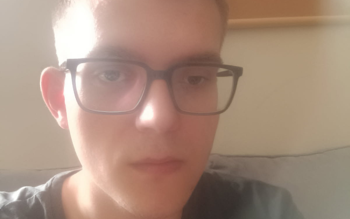 
        Młody mężczyzna w okularach, patrzący w stronę kamery.
    