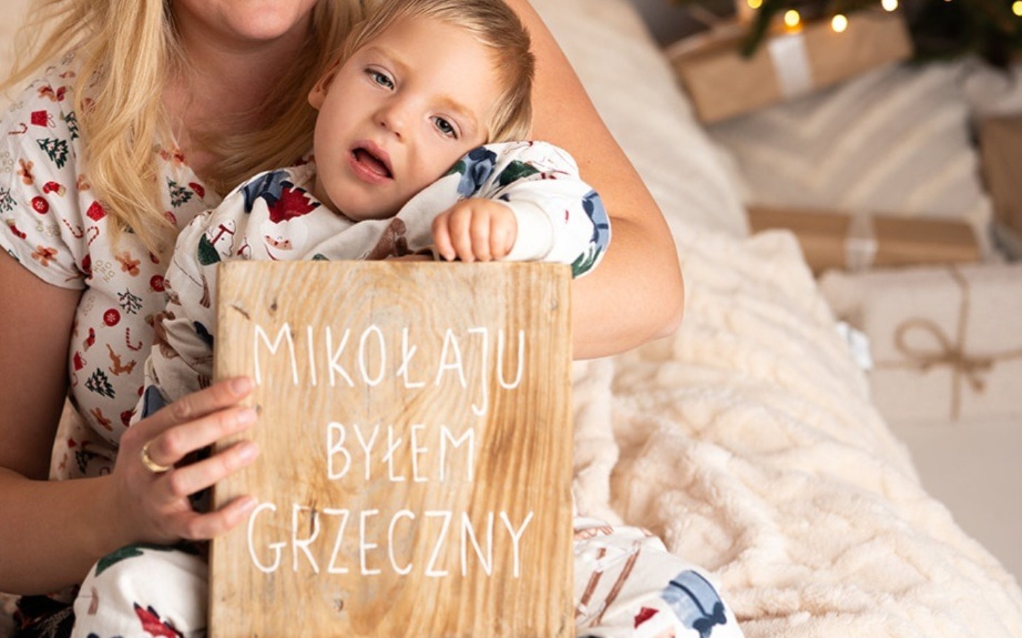 
        Dziecko trzymające tabliczkę z napisem o byciu grzecznym.
    