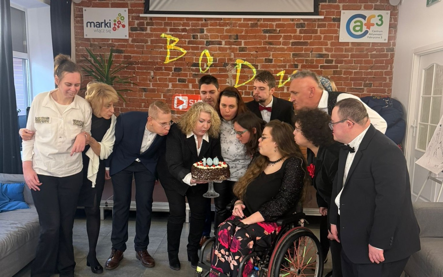 
        Grupa ludzi świętujących urodziny, z tortem.
    