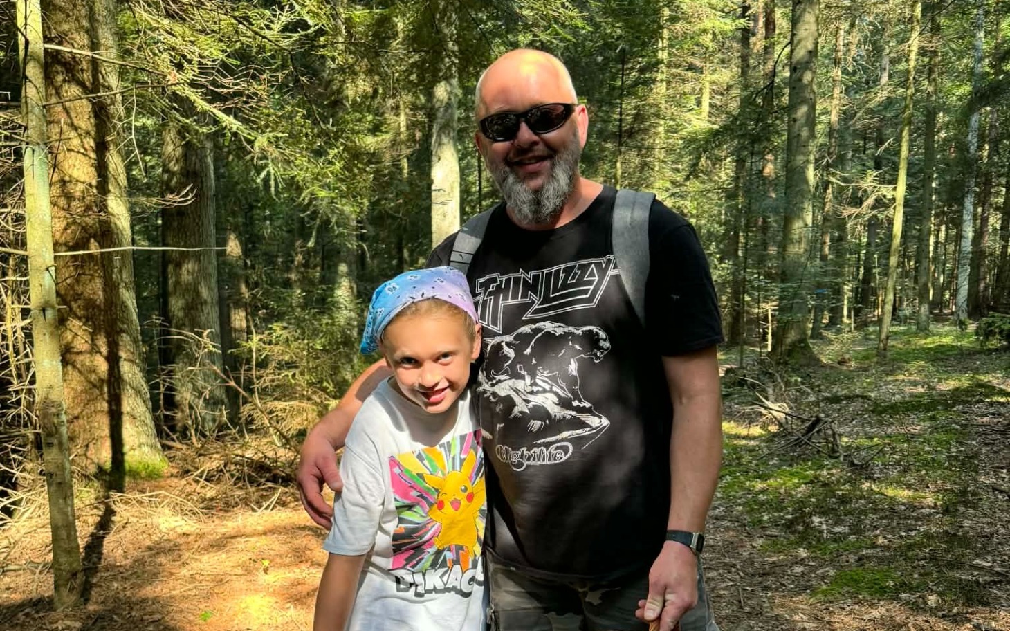 
        Dziecko i dorosły uśmiechają się w lesie, ciesząc się wspólnym czasem.
    