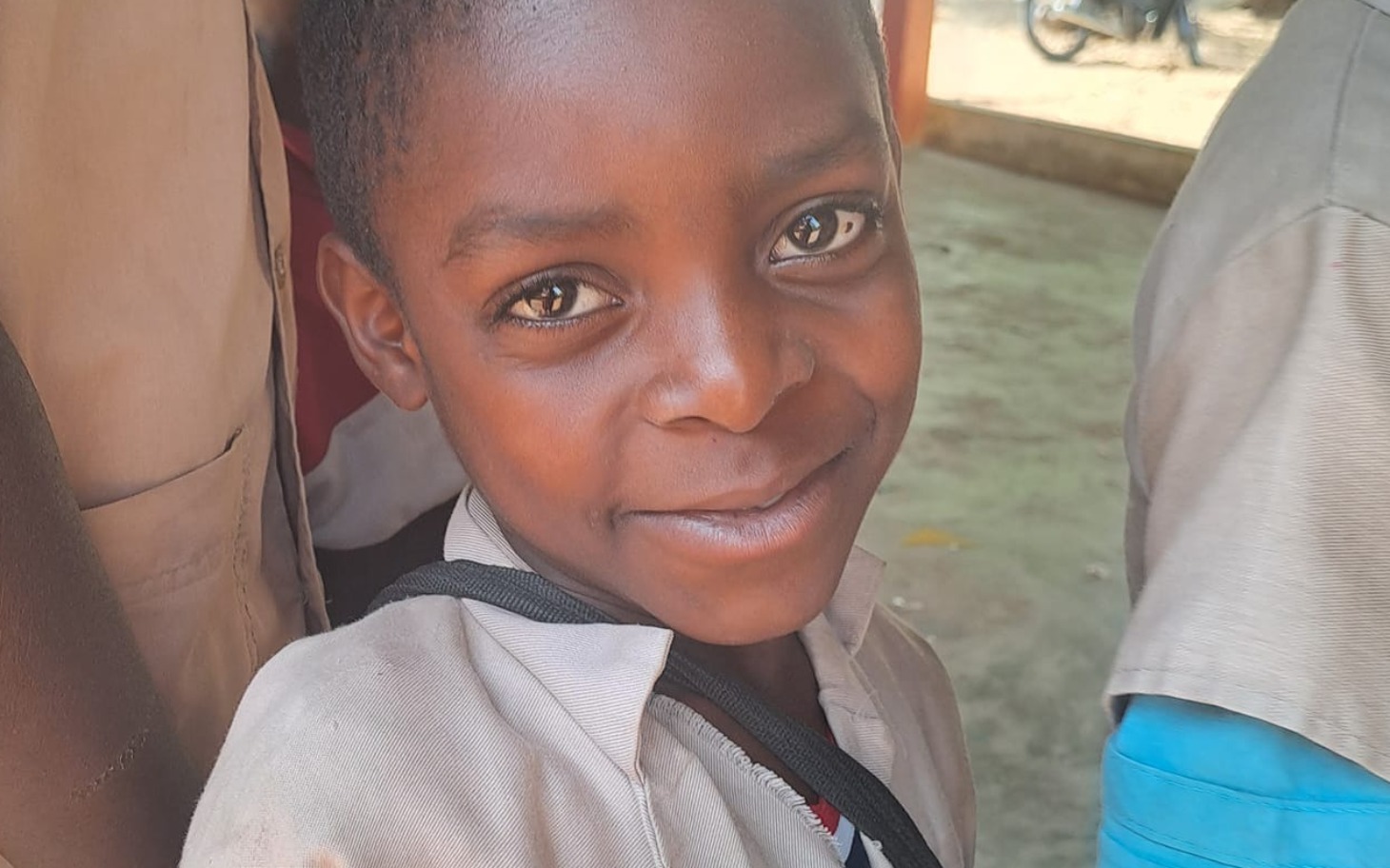 
        Uśmiechnięty chłopiec w szkolnym mundurku, pozujący do zdjęcia.
    