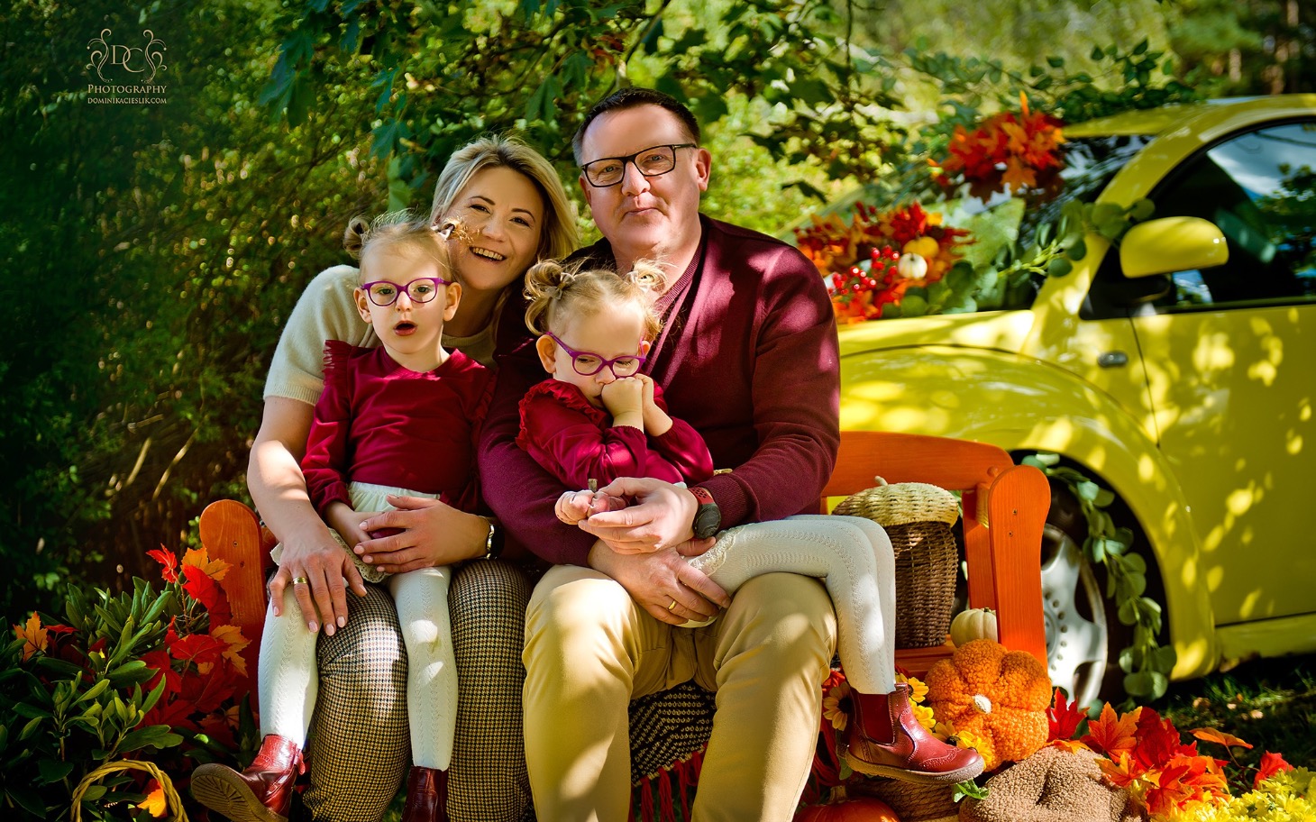 
        Rodzina pozująca na tle kolorowych liści i samochodu.
    