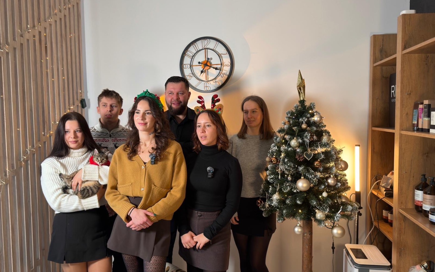 
        Grupa osób w świątecznych akcesoriach przy choince.
    