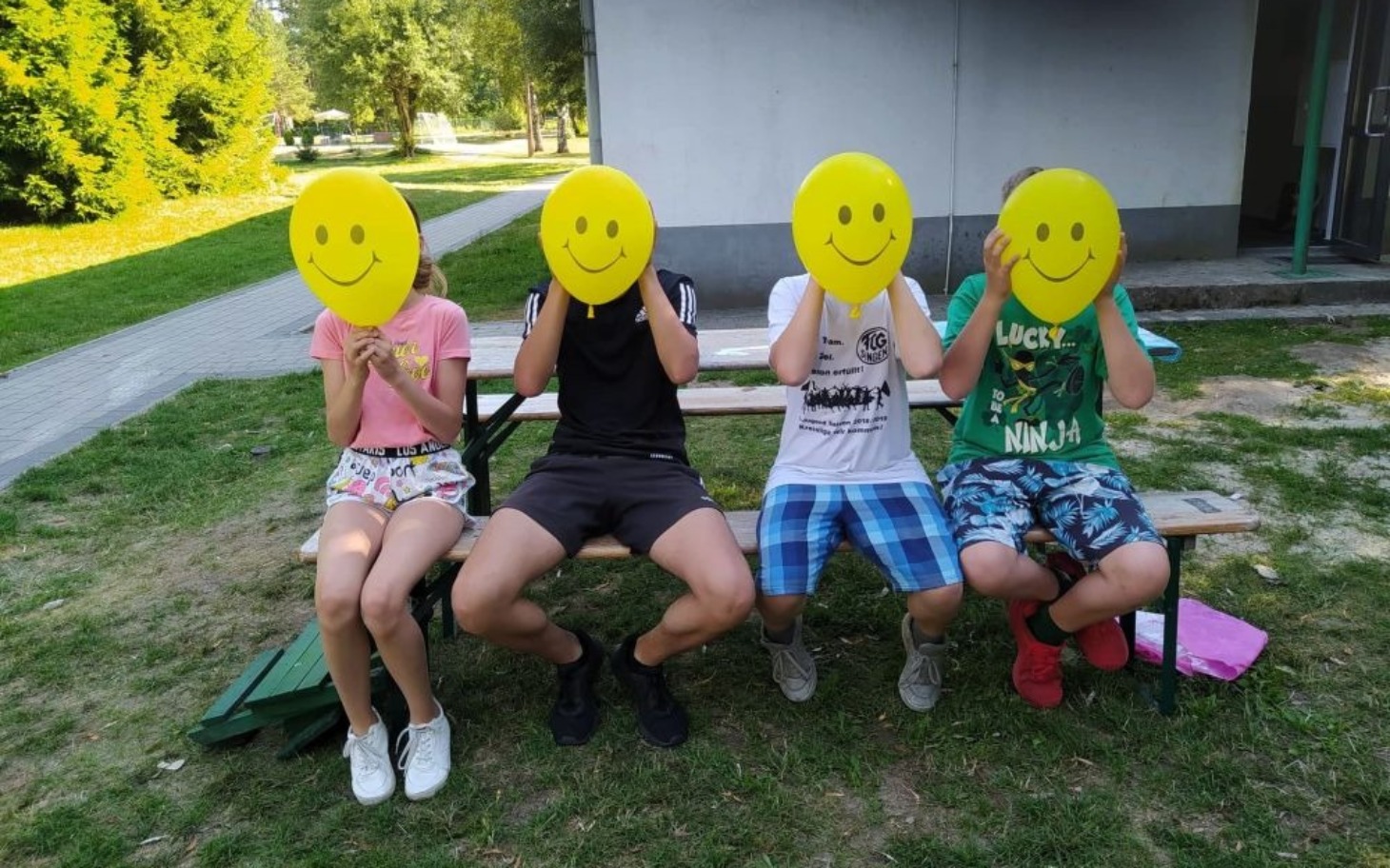 
        Czwórka dzieci z żółtymi balonami na twarzach.
    