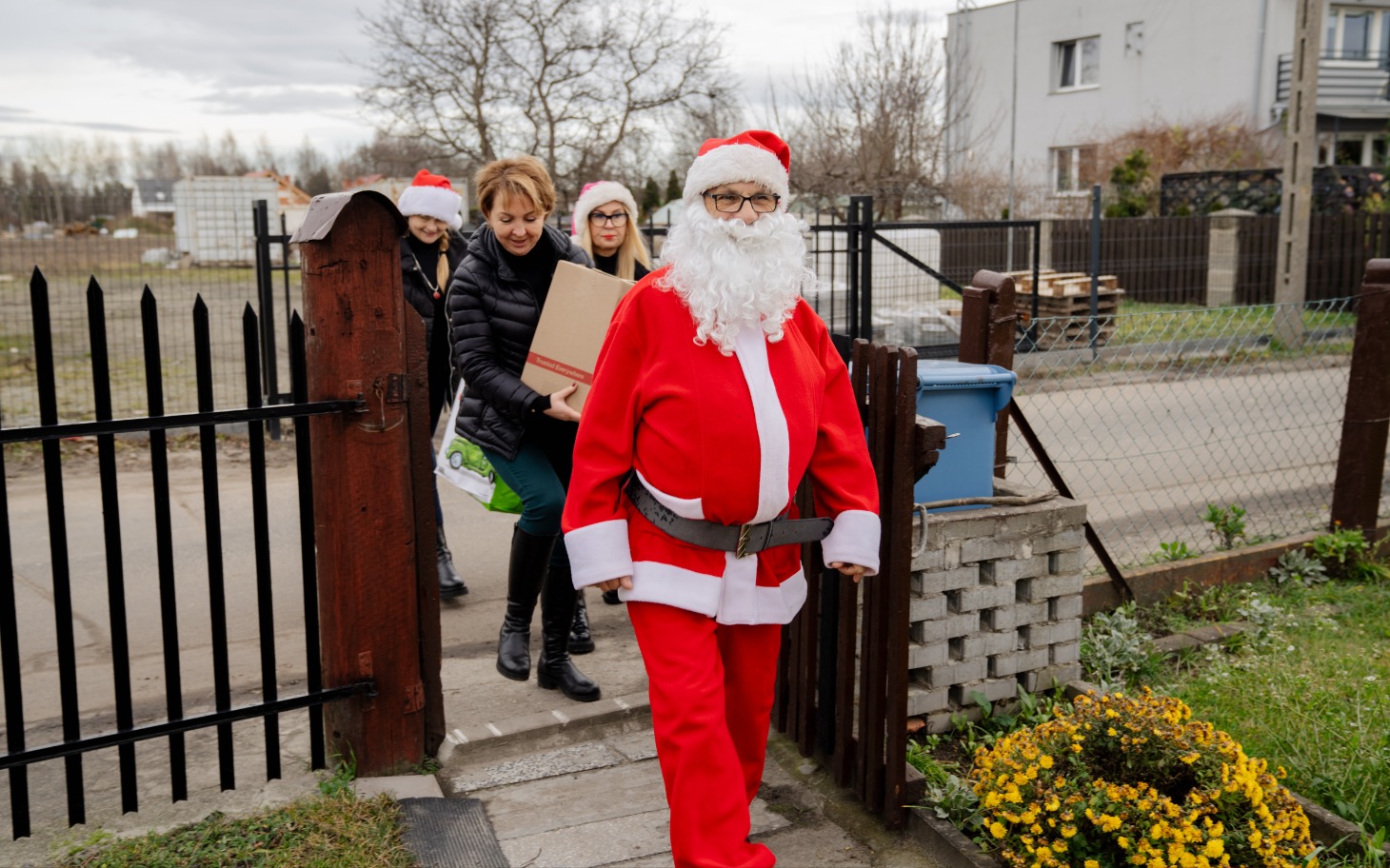 
        Mikołaj z paczką, otoczony przez uśmiechnięte kobiety.
    