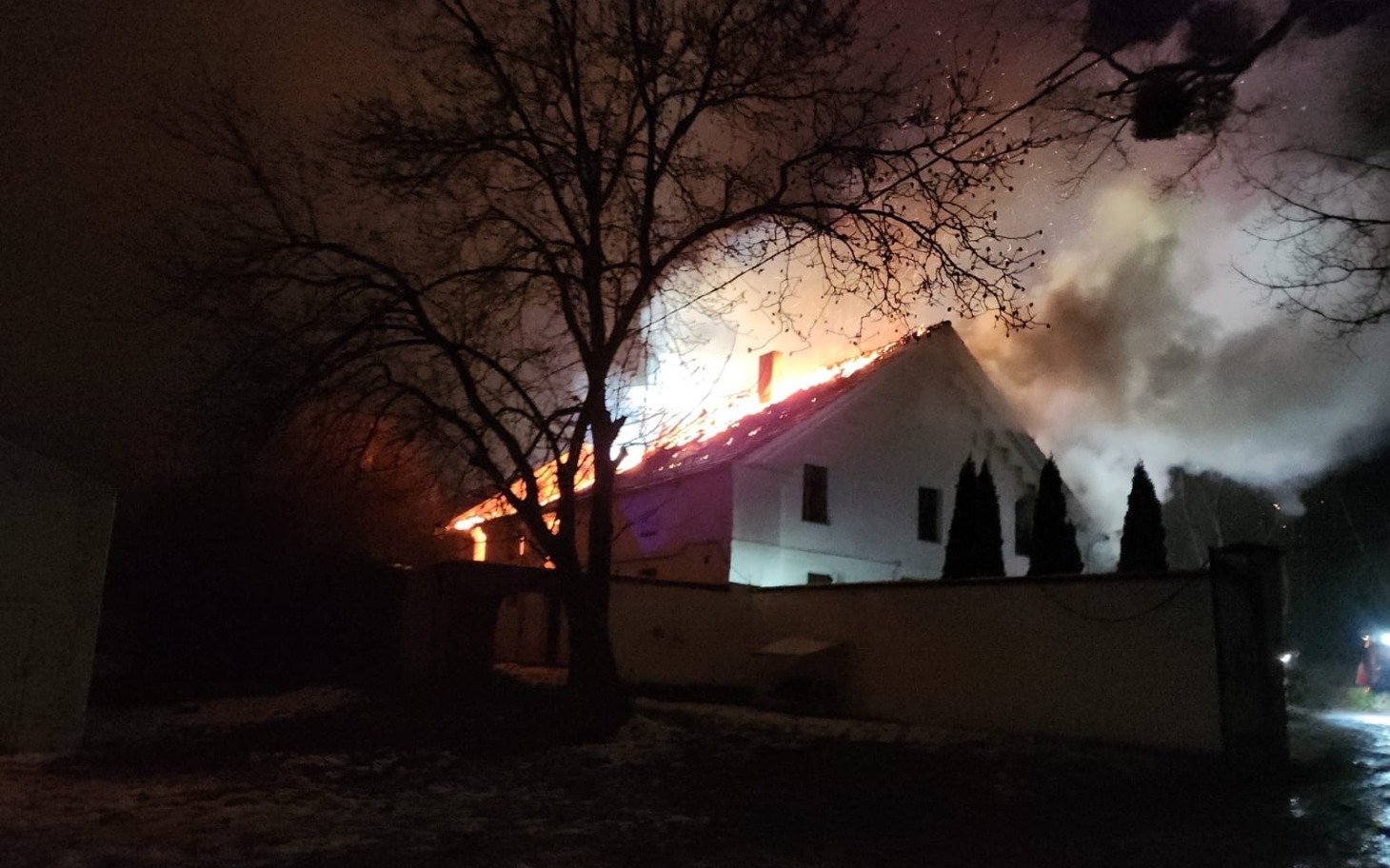 
        Pożar budynku w nocy, dym i płomienie.
    
