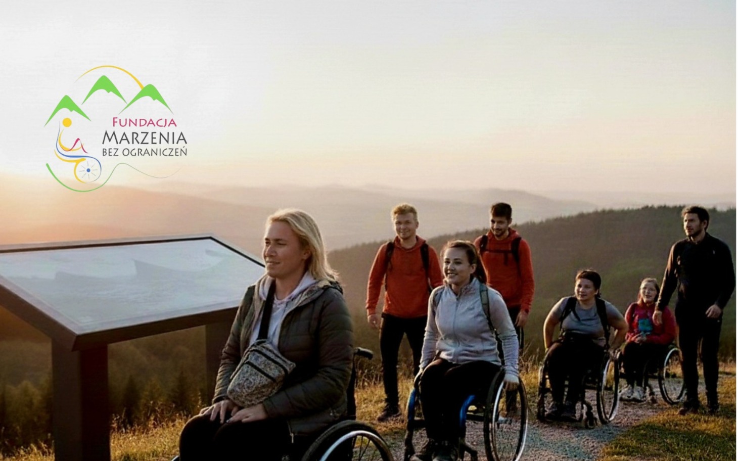 
        Grupa osób na wózkach inwalidzkich podczas wędrówki w górach.
    