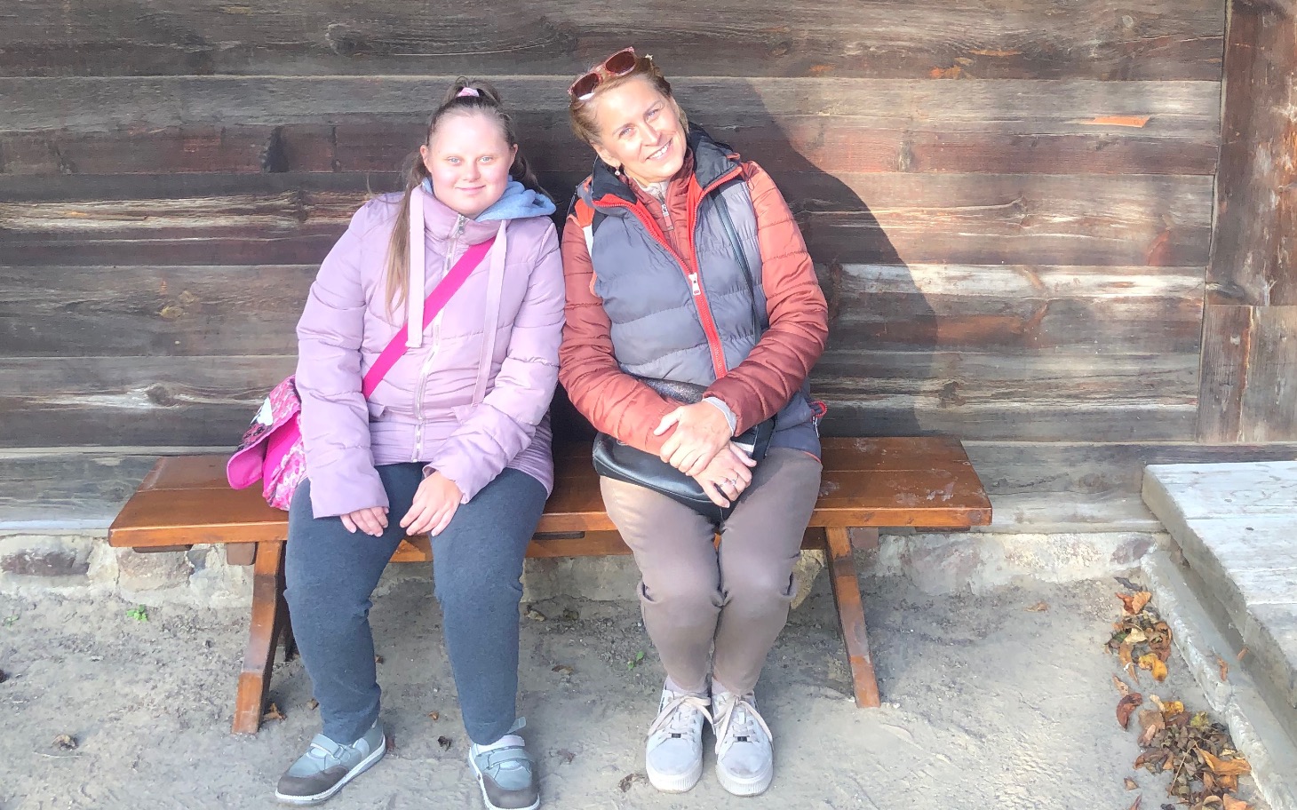 
        Dwie kobiety siedzące na ławce w plenerze.
    