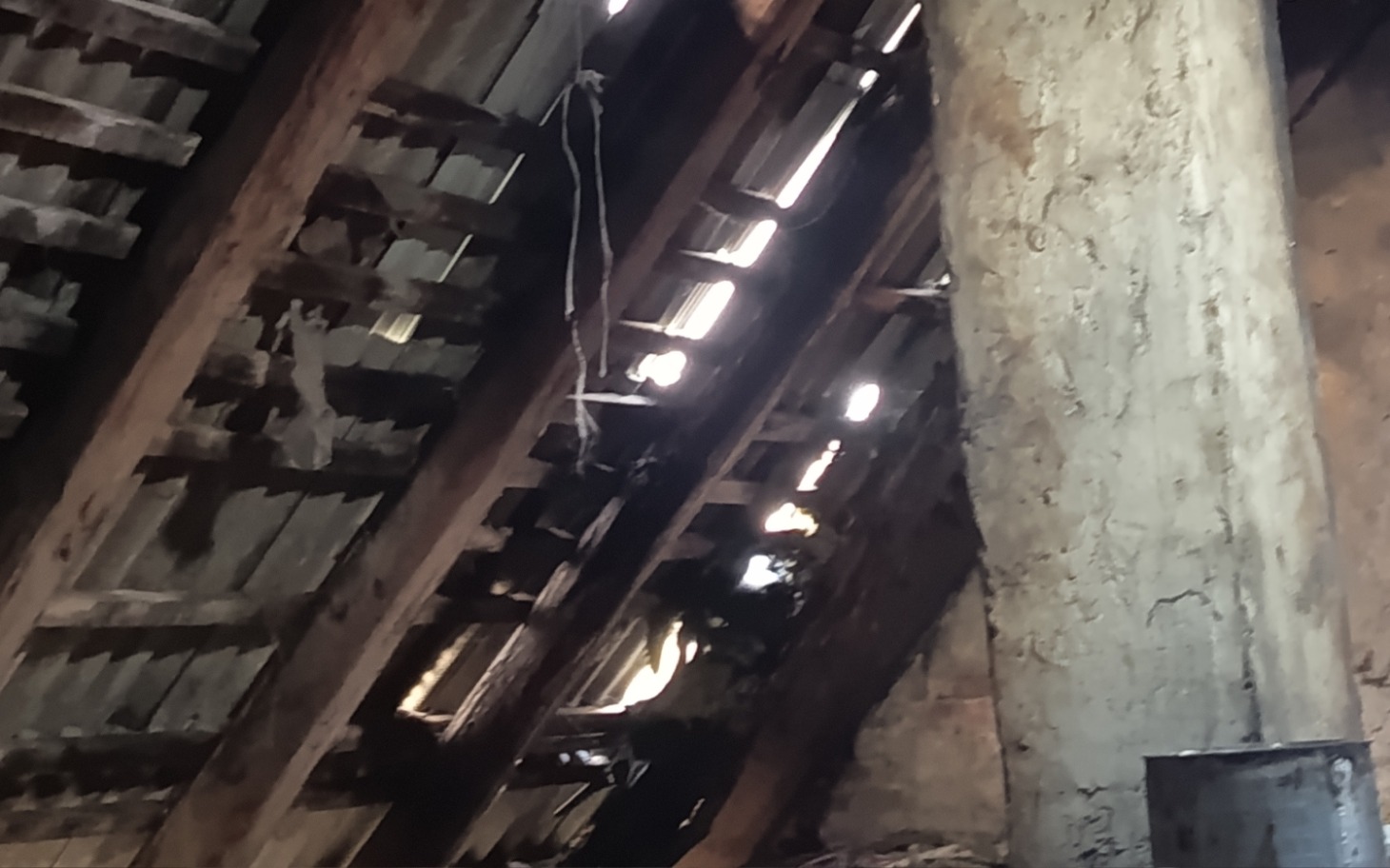 
        Widok na drewniany strop z promieniami światła wpadającymi przez szczeliny.
    