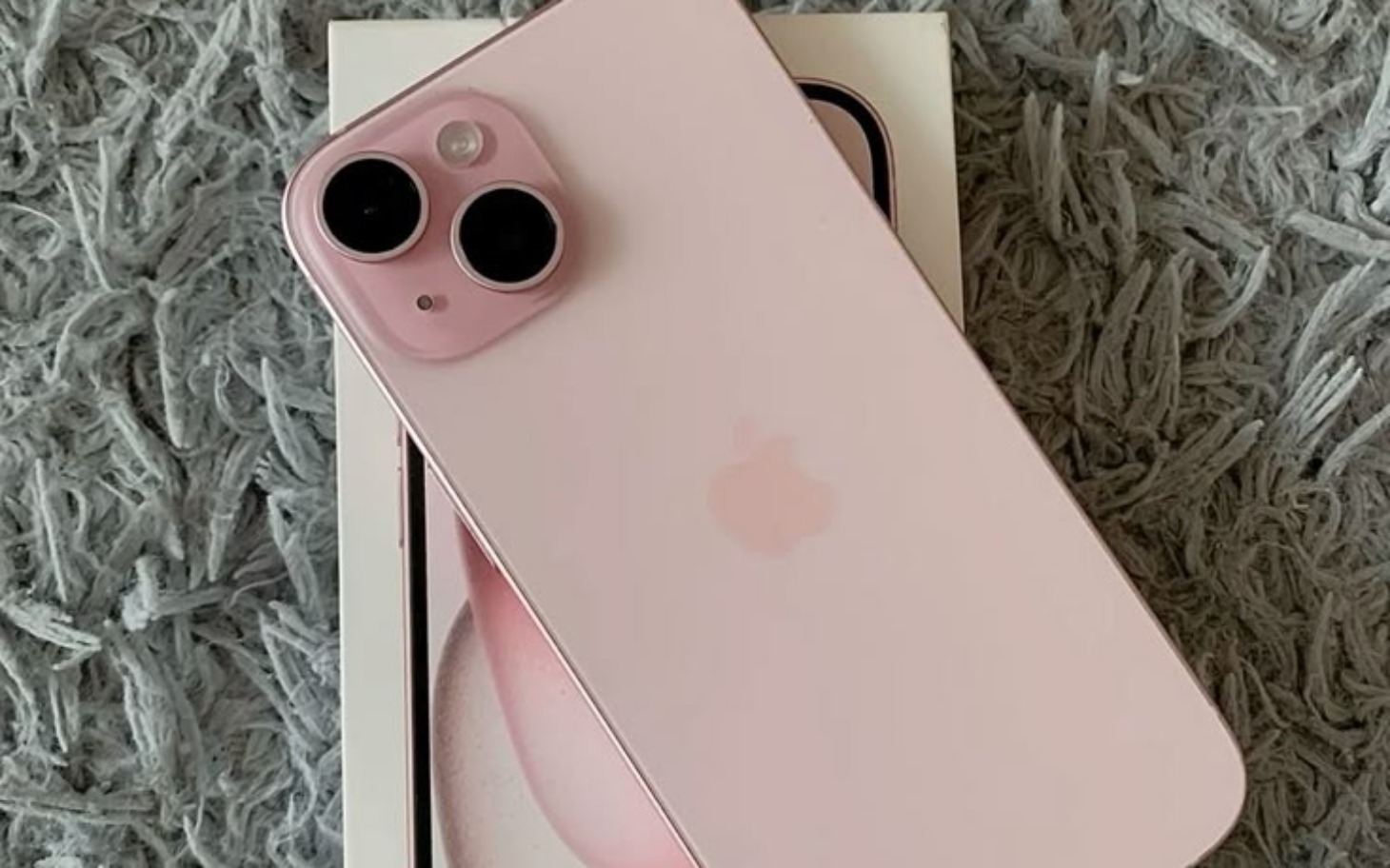 
        Różowy iPhone 13 na tle opakowania.
    