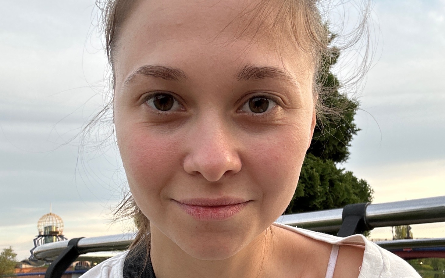 Młoda kobieta z naturalnym uśmiechem, pozująca na tle nieba.