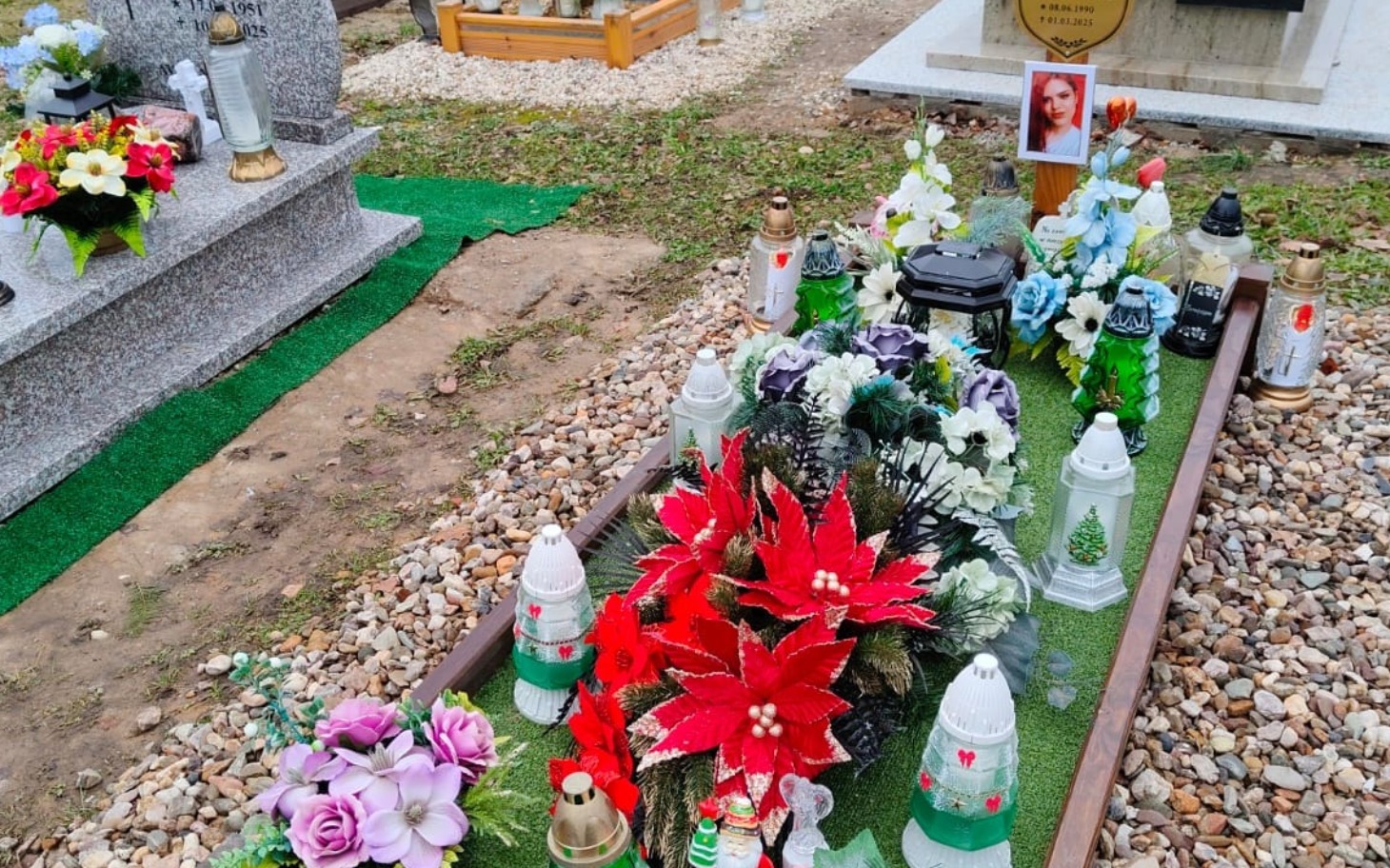
        Grób z kwiatami i zniczami, symbol pamięci o zmarłych.
    
