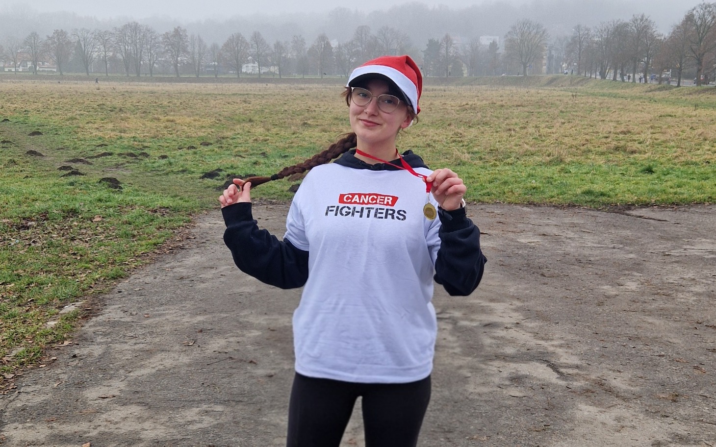 
        Osoba w koszulce 'CANCER FIGHTERS' z medalem.
    