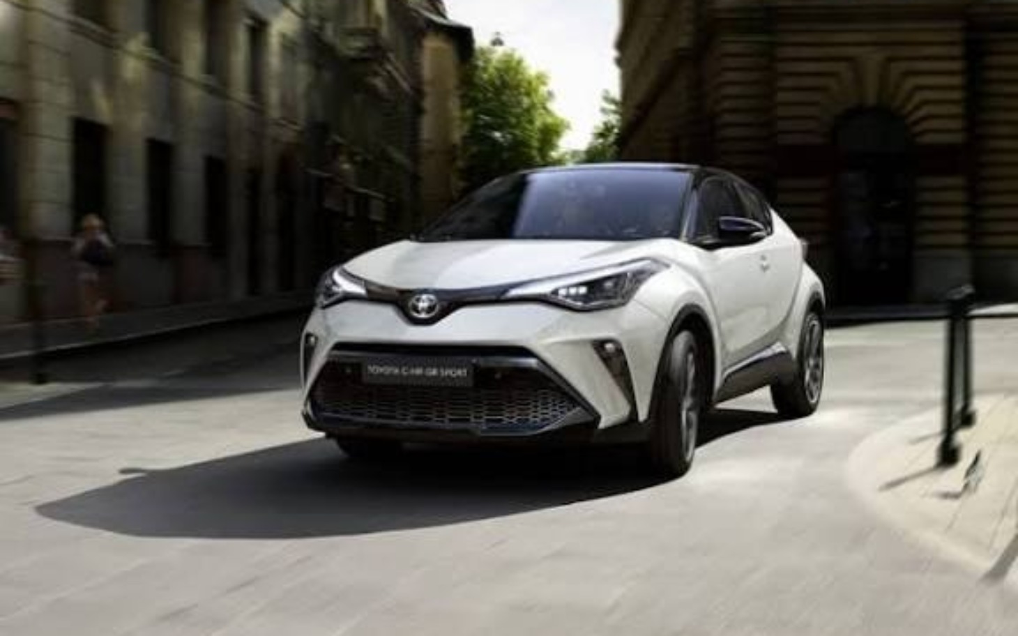 
        Nowoczesny samochód Toyota C-HR, jadący ulicą.
    