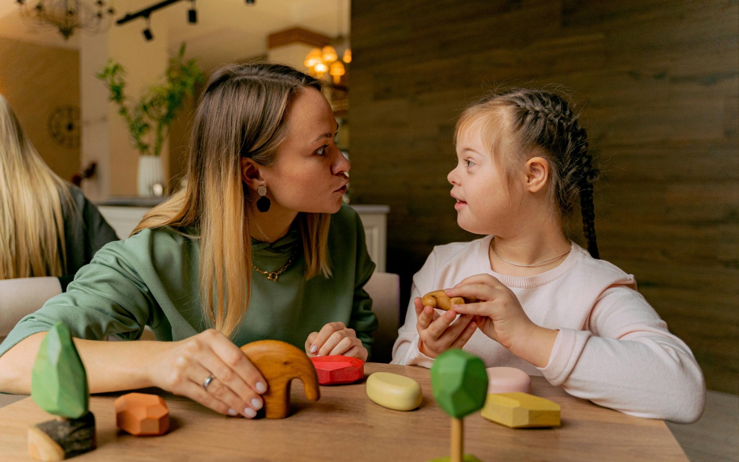 
        Kobieta i dziewczynka bawią się drewnianymi zabawkami.
    